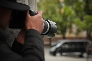 Photo of Private detective with modern camera spying on city street, closeup