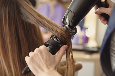 Photo of Professional hairdresser working with client in salon