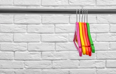 Clothes hangers on metal rail against brick wall background