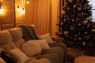 Photo of Comfortable sofa near Christmas tree in room