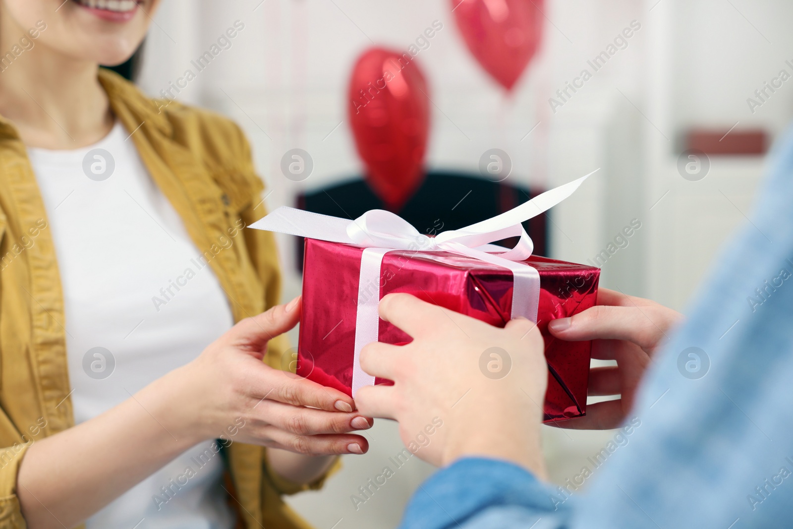 Photo of Woman receiving gift box from her boyfriend indoors, closeup. Valentine's day celebration.