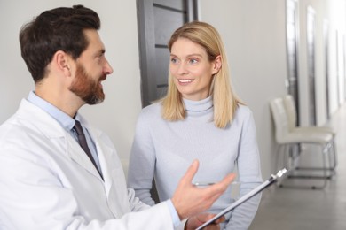Photo of Doctor with clipboard consulting happy patient in clinic