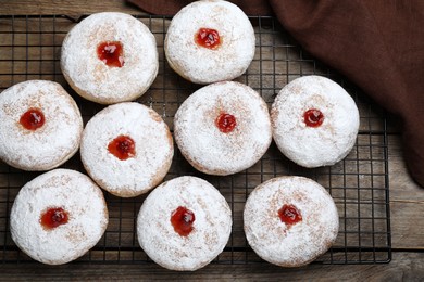 Many delicious donuts with jelly and powdered sugar on wooden table, top view