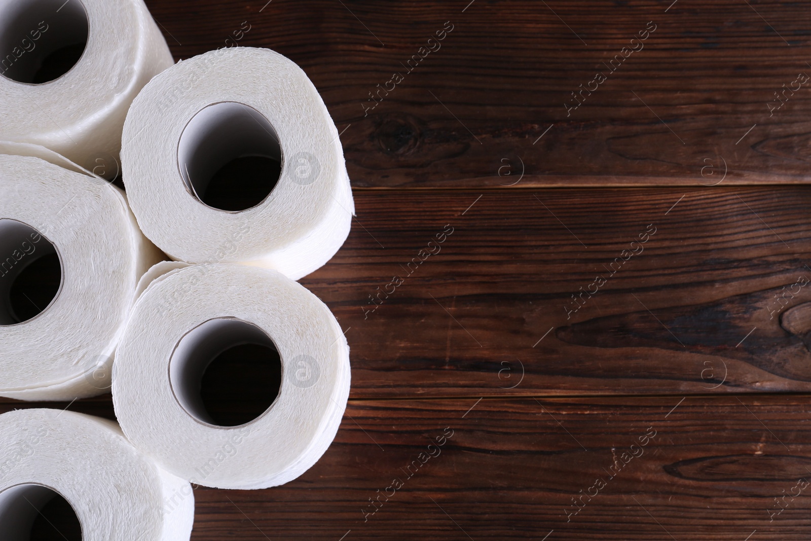 Photo of Many soft toilet paper rolls on wooden table, flat lay. Space for text