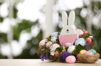 Photo of Festive composition with Easter eggs on table against blurred window, space for text