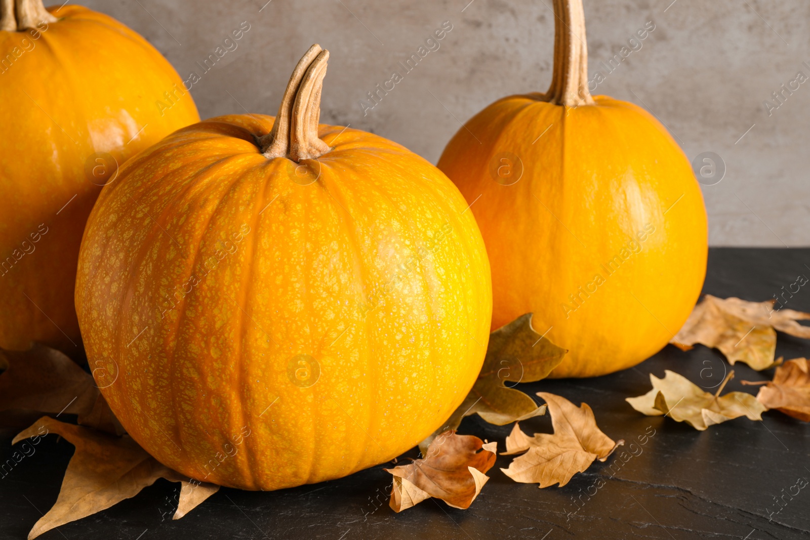 Photo of Ripe pumpkins and autumn leaves on black table