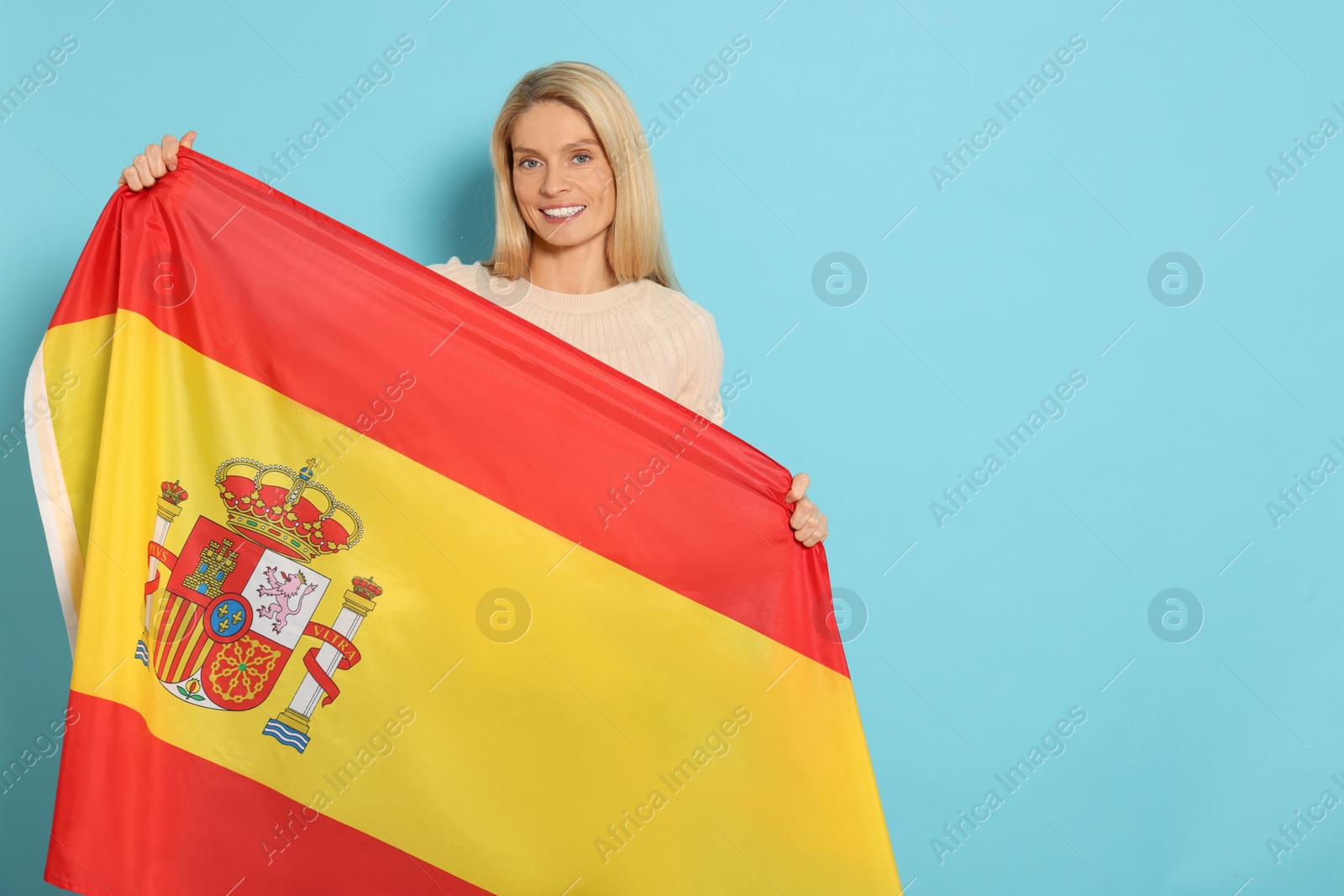 Photo of Woman with flag of Spain on light blue background, space for text