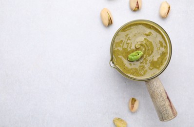 Photo of Tasty pistachio cream and nuts on white table, top view. Space for text