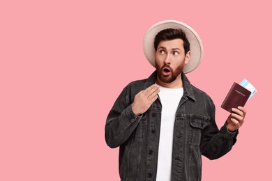 Photo of Surprised man with passport and tickets on pink background. Space for text