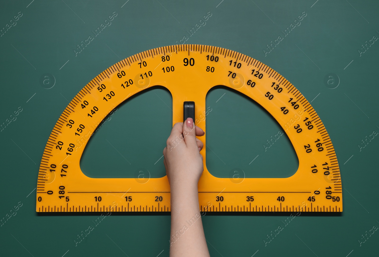 Photo of Woman holding protractor with measuring length and degrees markings near green board, closeup