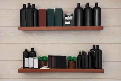Shelves with professional hair cosmetics on wall in barbershop