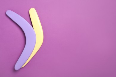 Photo of Colorful wooden boomerangs on purple background, flat lay. Space for text