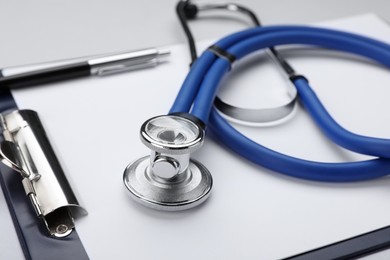 Stethoscope and clipboard on white background, closeup