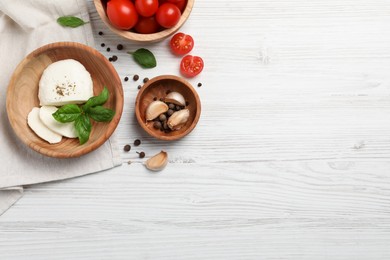 Photo of Delicious mozzarella with tomatoes and basil leaves on white wooden table, flat lay. Space for text