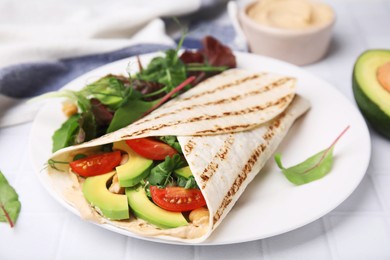 Plate with hummus wrap and vegetables on white table, closeup