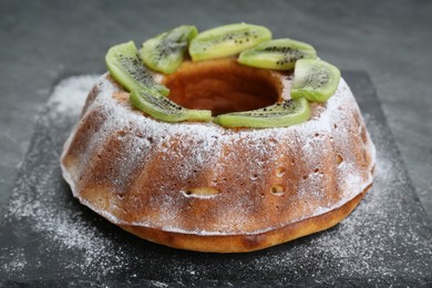 Homemade yogurt cake with kiwi and powdered sugar on black table