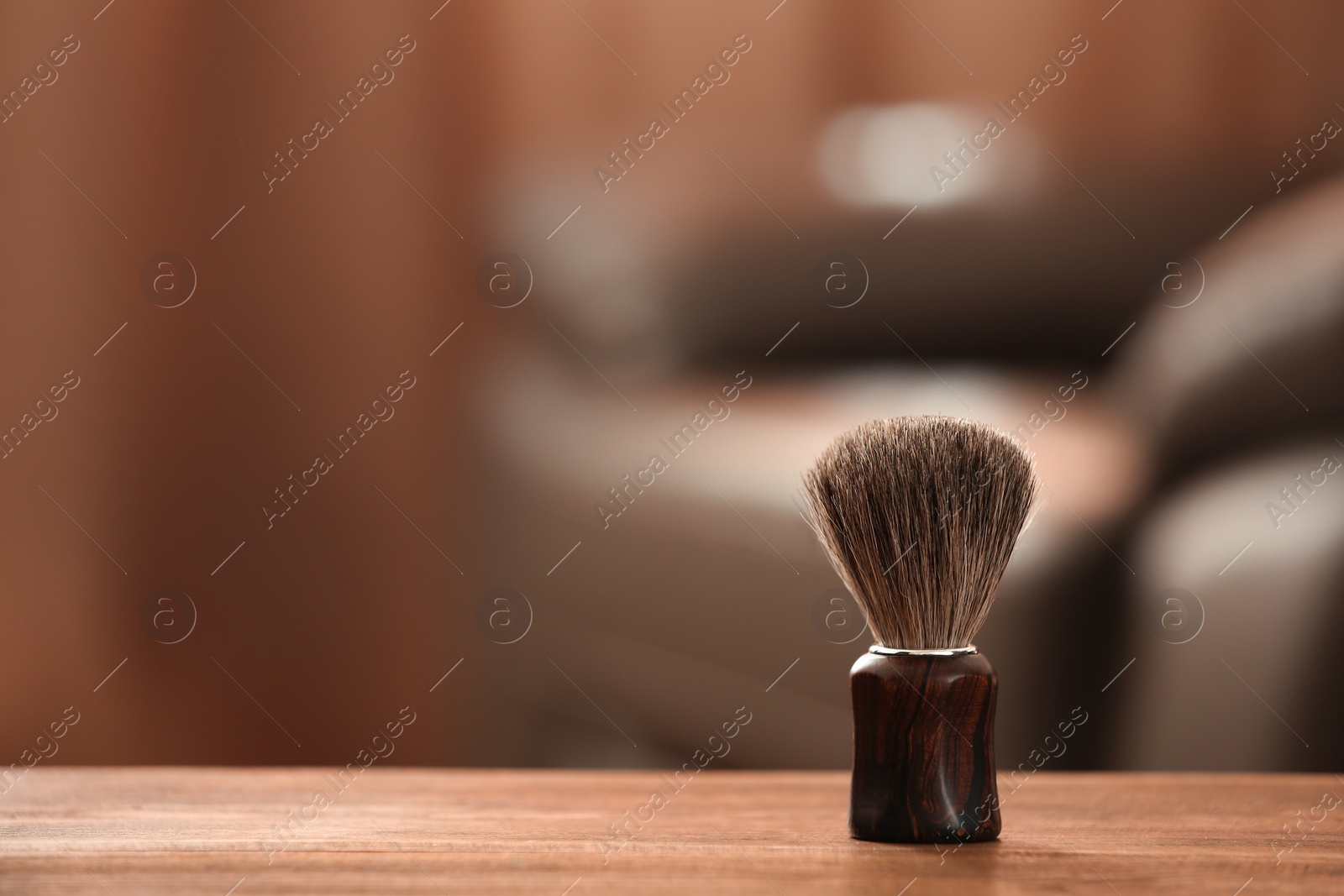 Photo of Shaving brush on table against blurred background with space for text