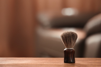 Shaving brush on table against blurred background with space for text