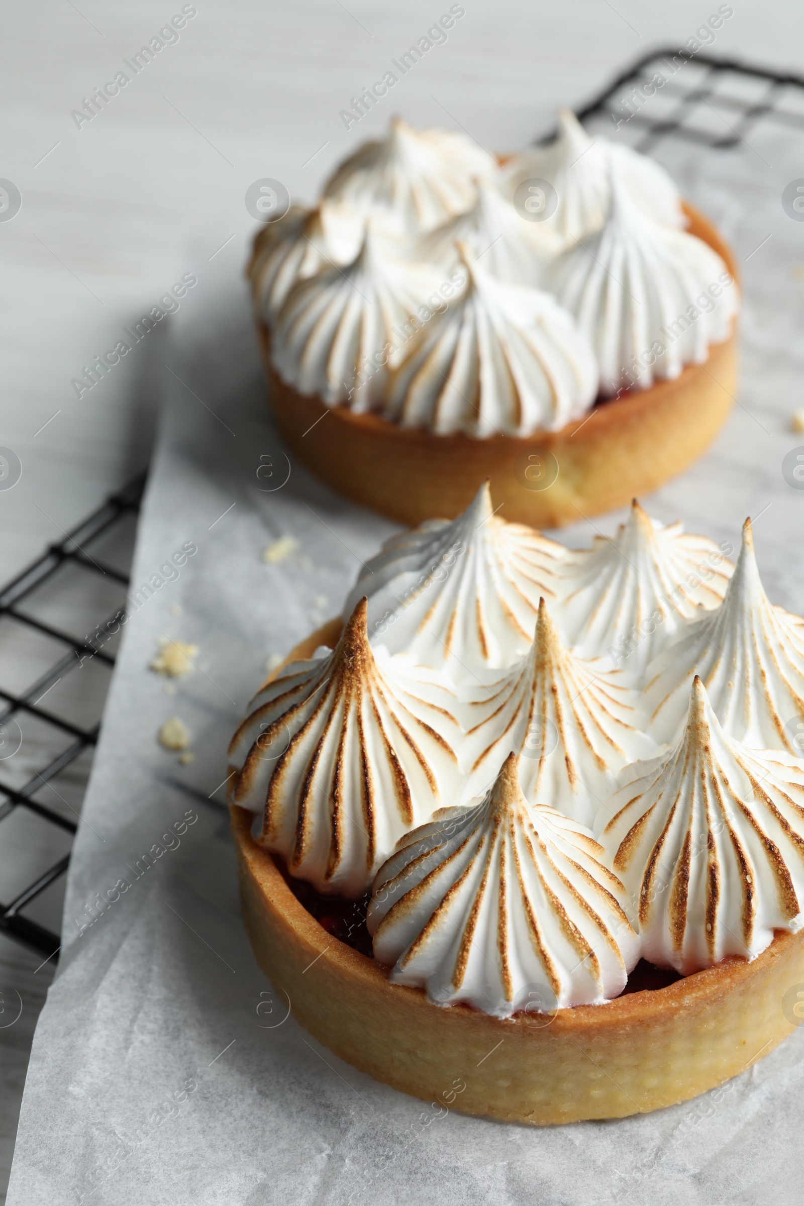 Photo of Tartlets with meringue on white table. Delicious dessert