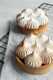 Photo of Tartlets with meringue on white table. Delicious dessert