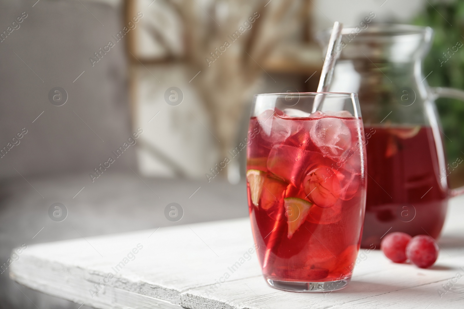 Photo of Grape soda water with ice and lime on white wooden table indoors, space for text. Refreshing drink