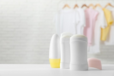 Photo of Different deodorants on white table in room. Space for text