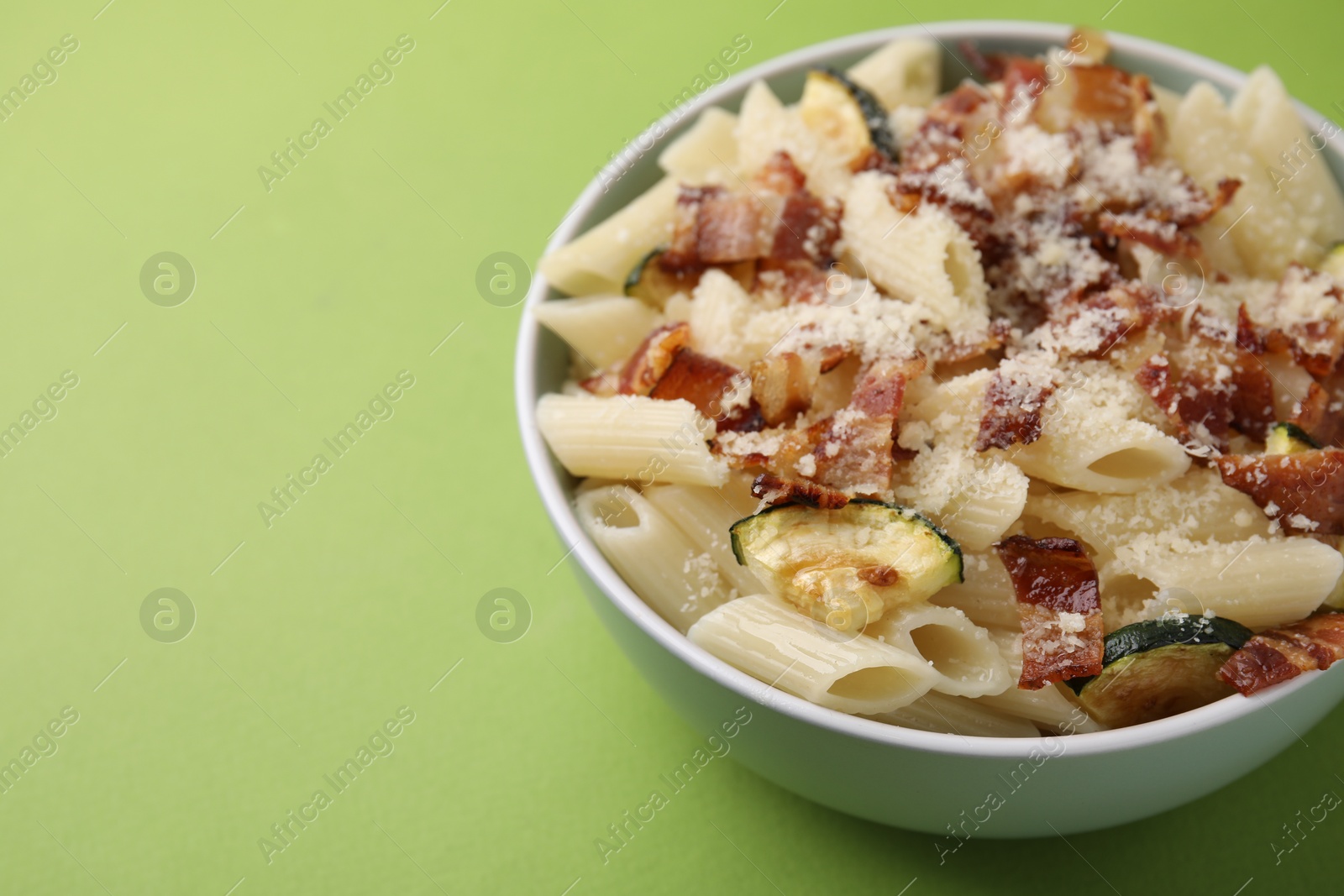 Photo of Tasty pasta with bacon and cheese on light green table, closeup. Space for text