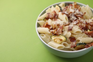 Photo of Tasty pasta with bacon and cheese on light green table, closeup. Space for text