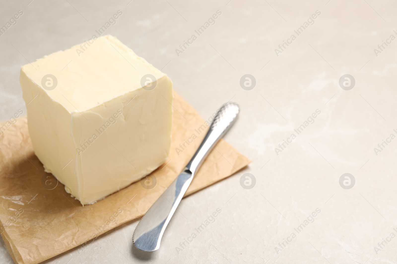 Photo of Block of tasty butter and knife on light table. Space for text