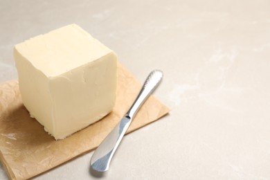 Block of tasty butter and knife on light table. Space for text