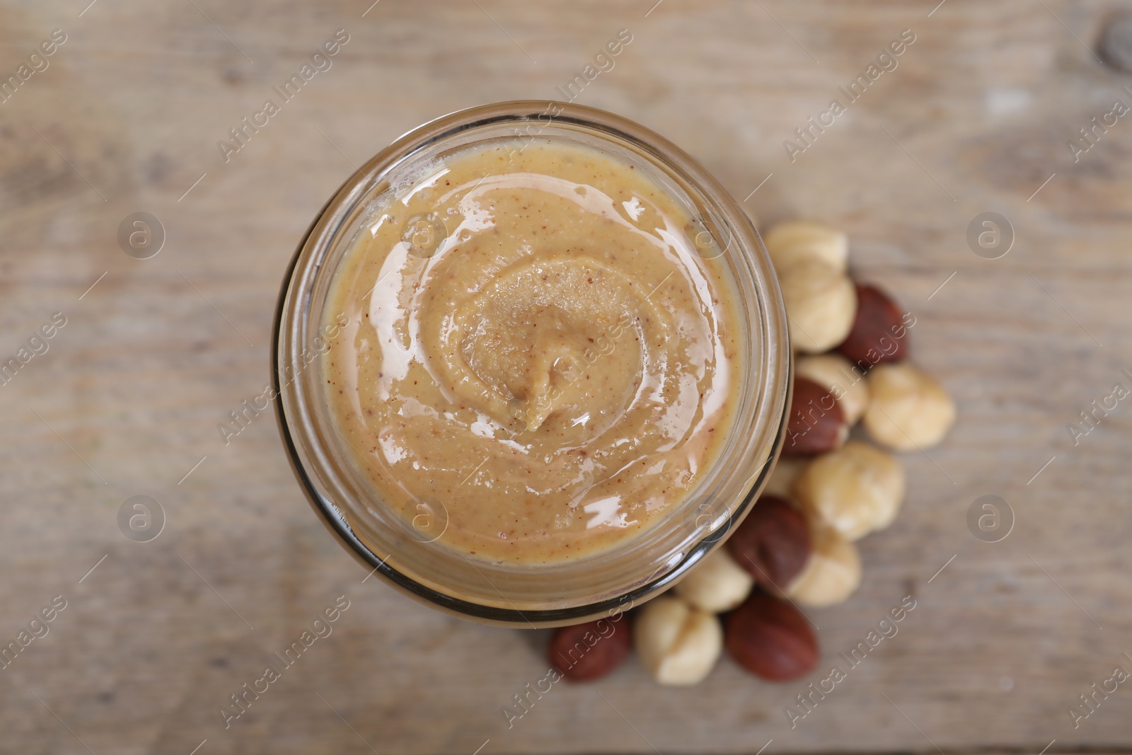 Photo of Tasty hazelnut nut paste in jar on table, top view