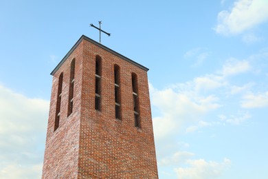 Photo of Beautiful brick church tower against blue sky, low angle view