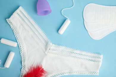 Photo of Flat lay composition with menstrual pads and panties on light blue background