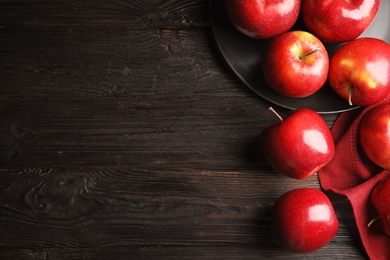 Flat lay composition with ripe juicy red apples on black wooden table. Space for text