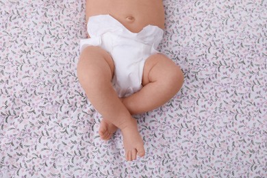 Photo of Little baby in diaper on bed, top view