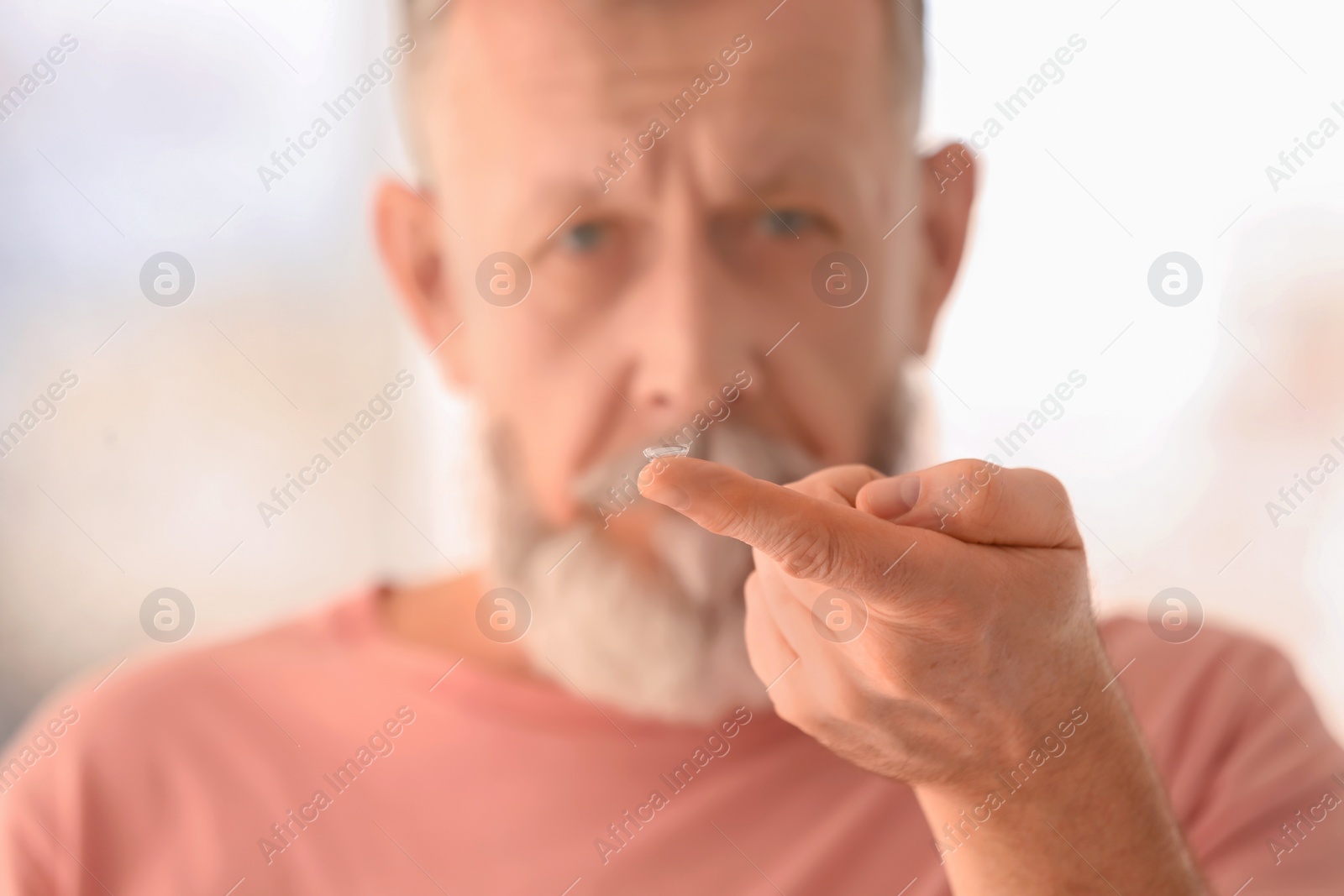 Photo of Senior man with contact lens on blurred background