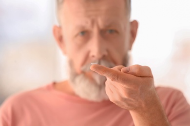 Senior man with contact lens on blurred background