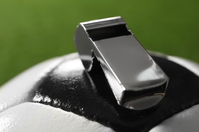Photo of Football referee. Soccer ball and metal whistle on green background, closeup