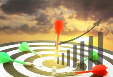 Image of Darts hitting target on board, illustration of graph and blurred of view sky at sunset
