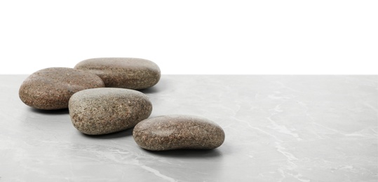 Photo of Spa stones on light grey table against white background. Space for text