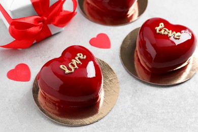 Photo of St. Valentine's Day. Delicious heart shaped cakes and gift on light table, closeup