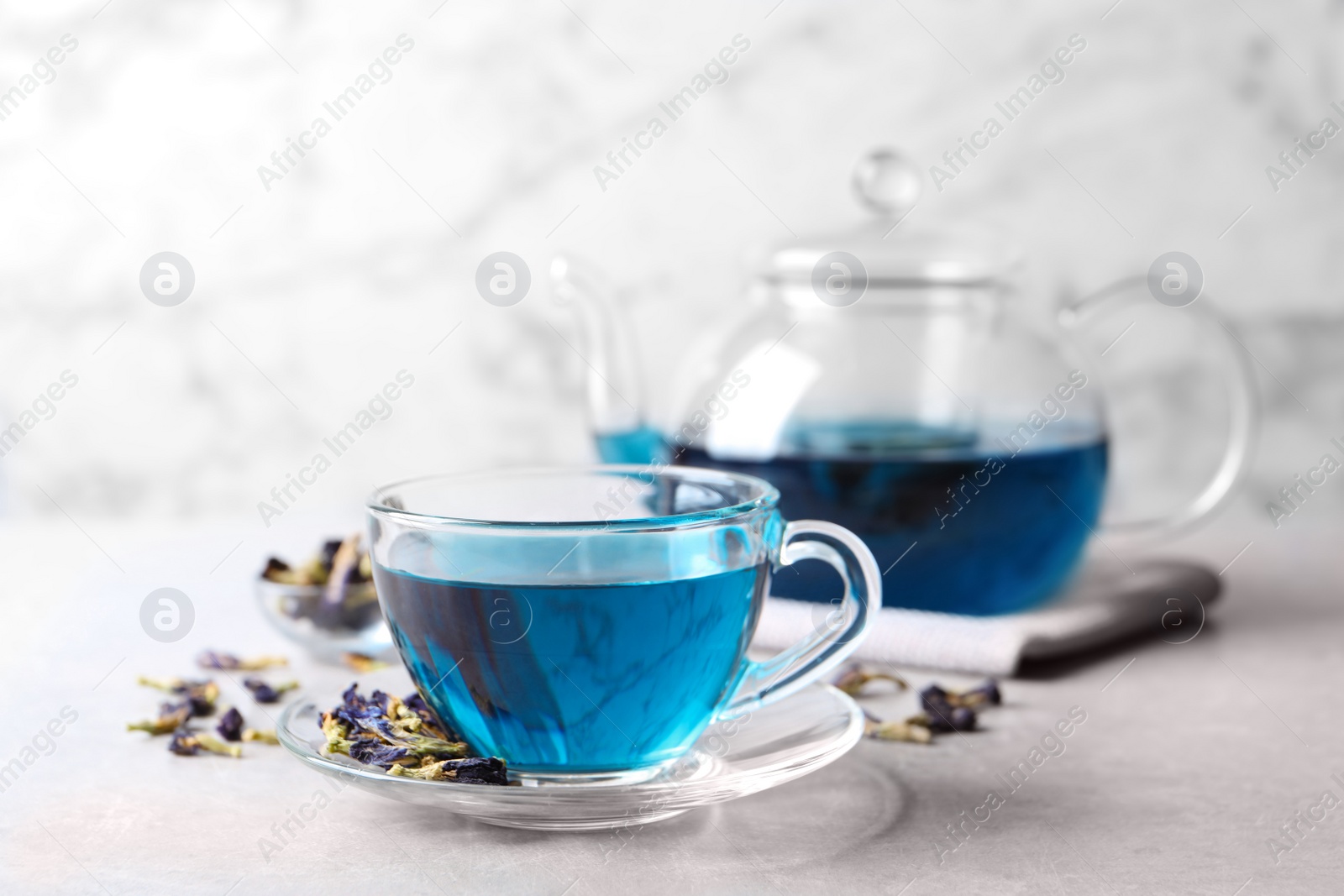 Photo of Glass cup of organic blue Anchan on light table, space for text. Herbal tea