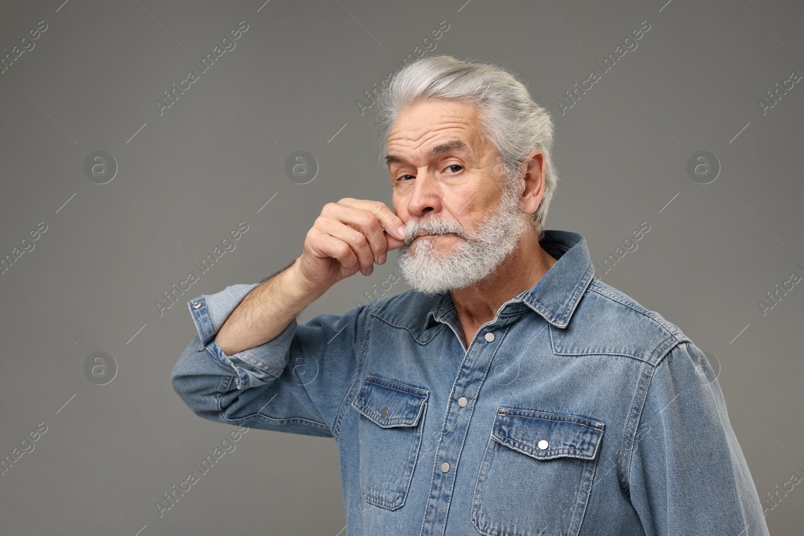 Photo of Senior man touching mustache on grey background