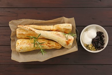 Tasty baked parsnips with rosemary and other ingredients on wooden table, flat lay