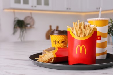 MYKOLAIV, UKRAINE - AUGUST 12, 2021: Two big portions of McDonald's French fries and drinks on marble table in kitchen. Space for text