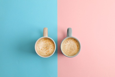 Cups of coffee on color background, top view