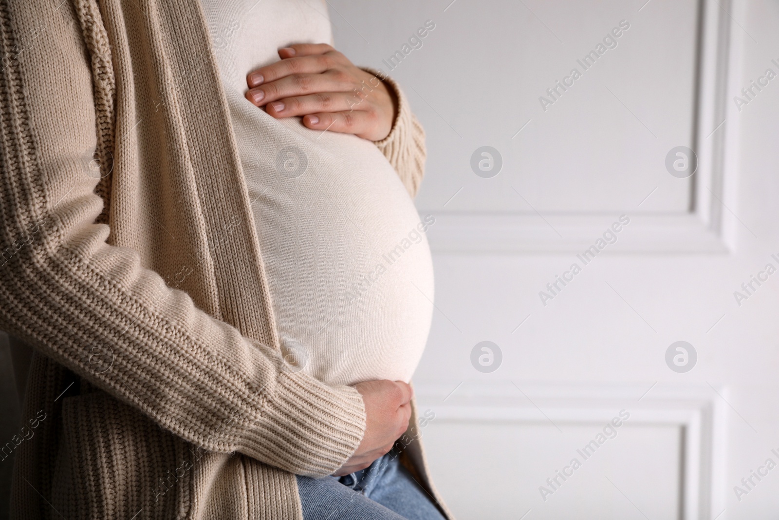 Photo of Young pregnant woman at home, closeup view. Space for text