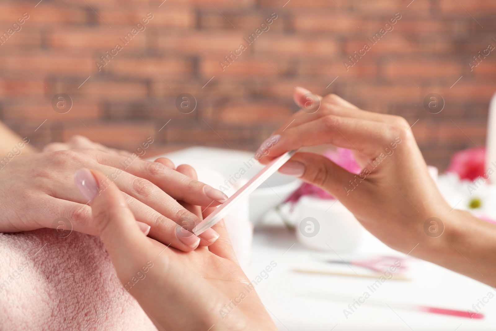 Photo of Manicurist filing client's nails at table, closeup. Spa treatment