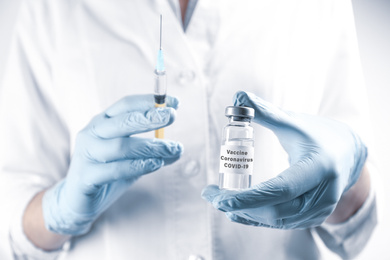 Doctor holding coronavirus vaccine and syringe, closeup