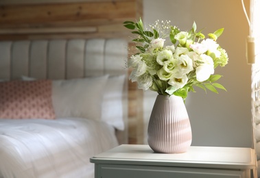 Photo of Bouquet of beautiful flowers on nightstand in bedroom, space for text. Interior design